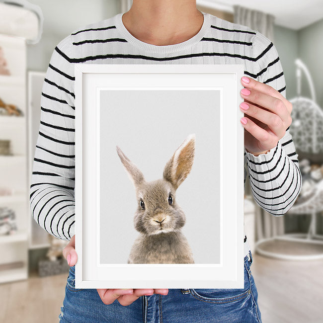 woman holding a picture of a cute rabbit in a white frame