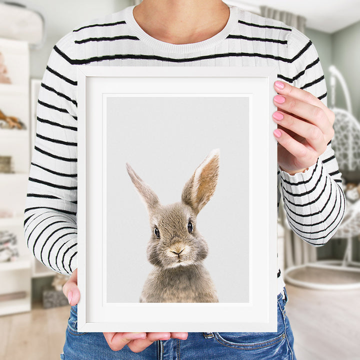 a brown bunny rabbit print in a white frame, situated in a nursery